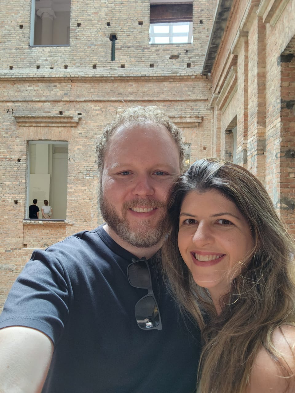 Giovanna e Carlos Augusto em um museu de paredes de tijolos