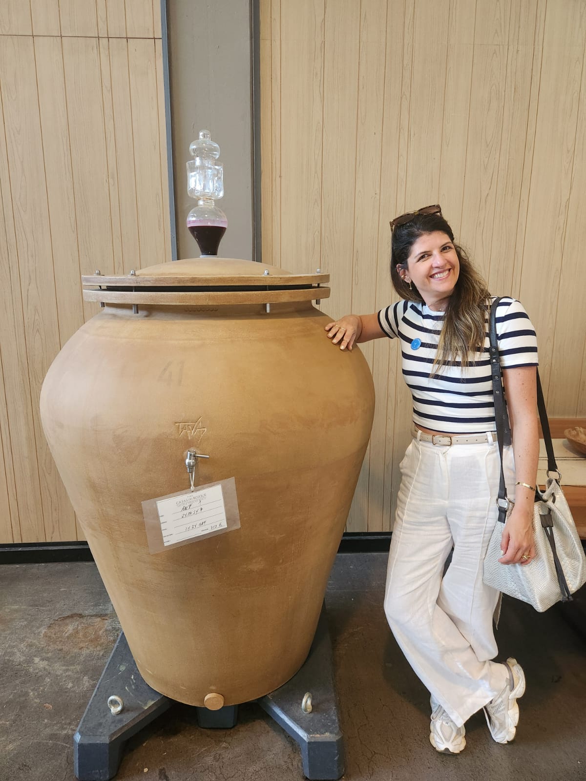 Giovanna ao lado de uma grande ânfora em uma vinícola