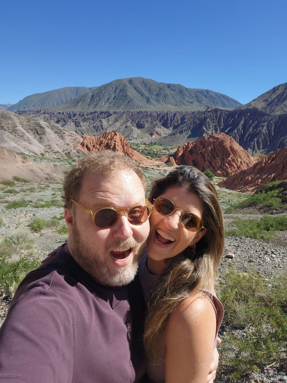 Giovanna e Carlos Augusto sorrindo entre formações montanhosas
